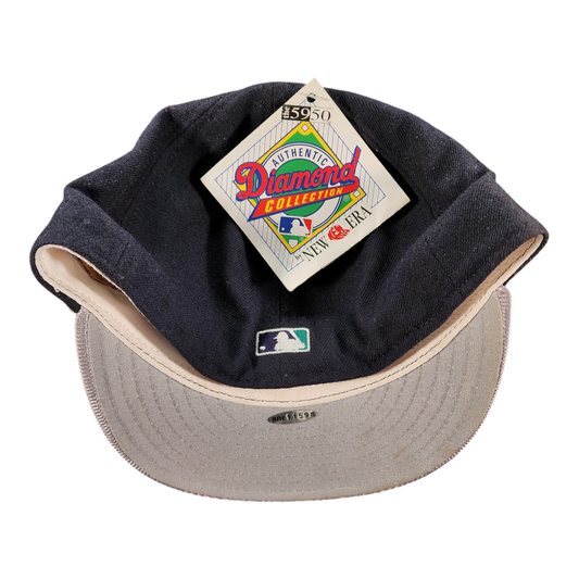 A vintage baseball cap by New Era, featuring a dark navy blue crown with a beige underside and a matching beige visor. The cap has an attached 'Authentic Diamond Collection' hangtag and a small MLB logo on the front.
