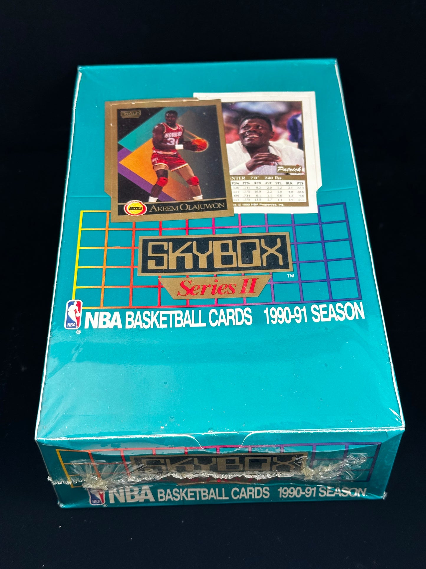 A sealed 1990-91 NBA Basketball Cards Skybox Series II trading card box in turquoise, with two sample cards attached on top, photographed against a black background.