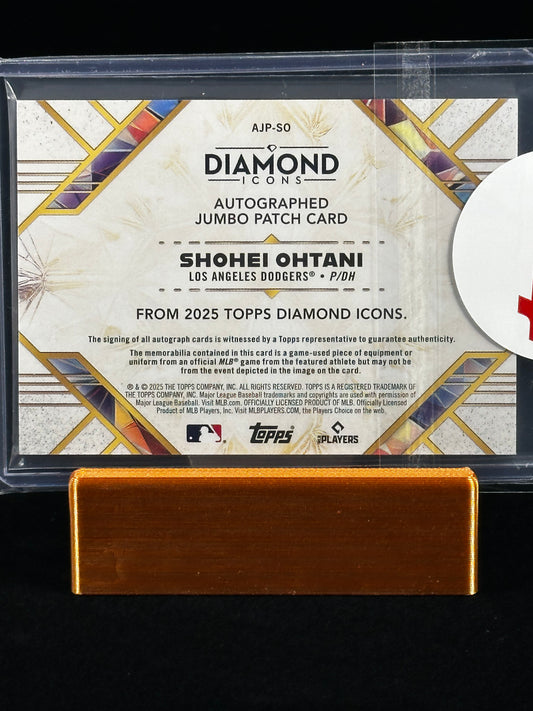 A Topps Diamond Icons autographed jumbo patch card featuring Shohei Ohtani, displayed in a clear protective case with a gold-colored metal stand against a black background.