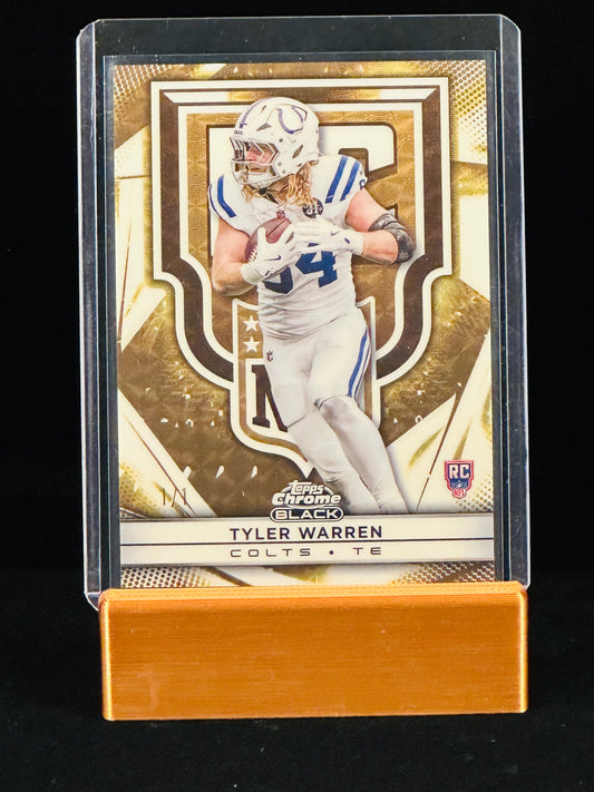 A collectible football trading card of Tyler Warren, Indianapolis Colts tight end, displayed in a clear protective case on a gold stand against a black background.