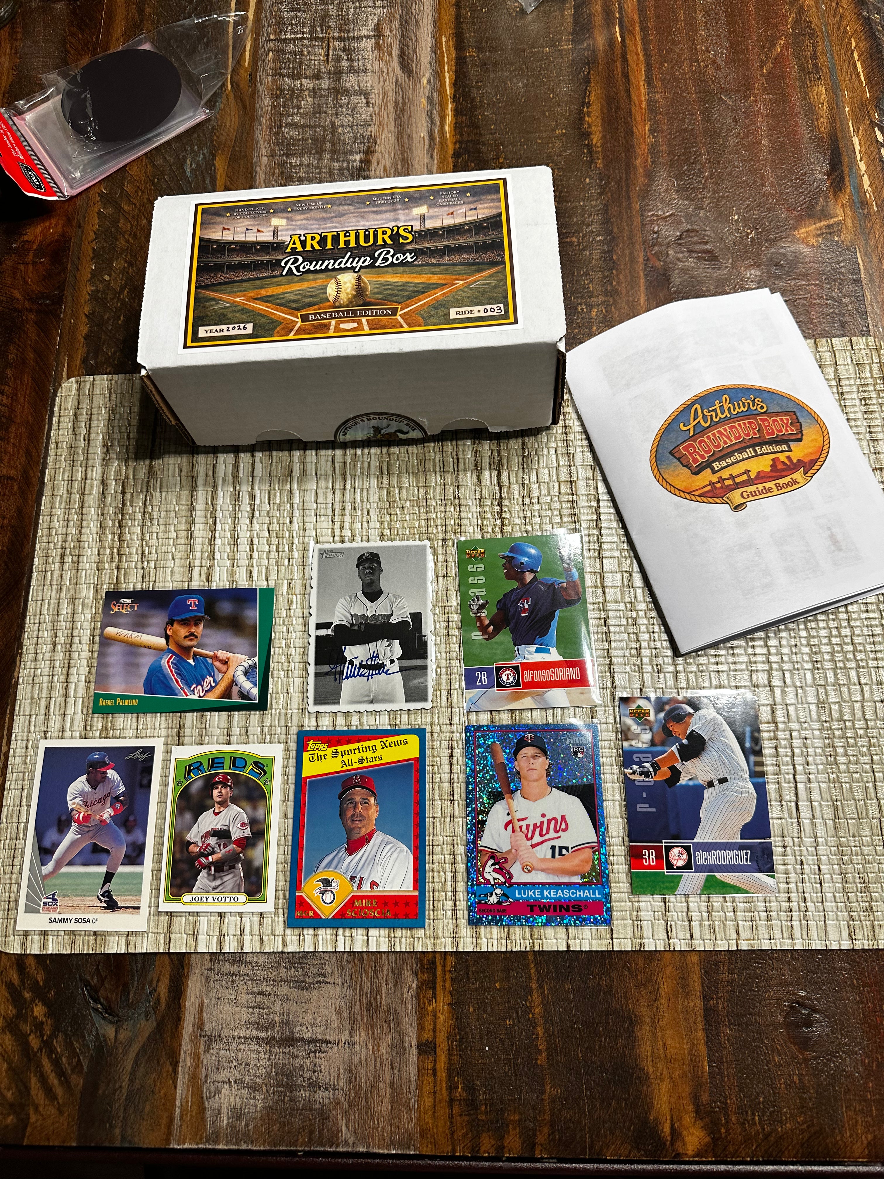Collection of baseball trading cards on a wooden surface with a box and paper.