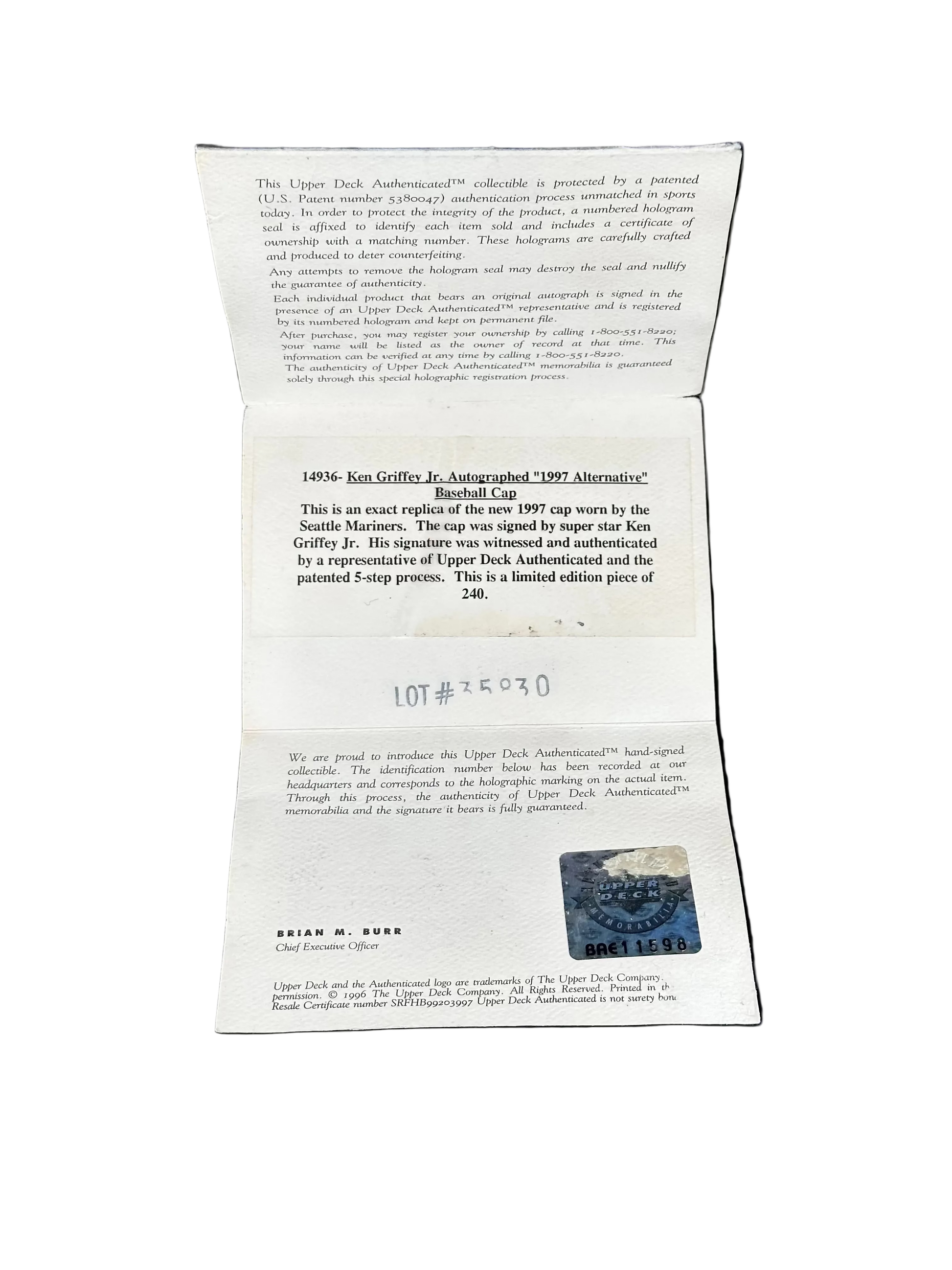 An open white paper document or certificate laid flat against a black background, showing printed text, a small blue stamp-like mark, and handwritten lot notation.