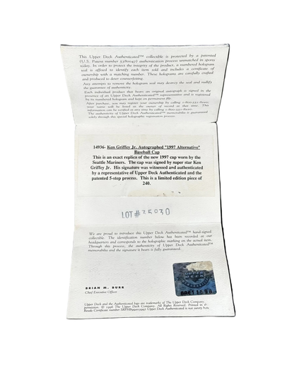 An open white paper document or certificate laid flat against a black background, showing printed text, a small blue stamp-like mark, and handwritten lot notation.