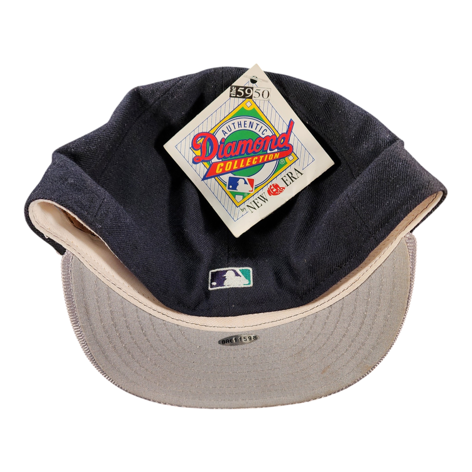 A vintage baseball cap by New Era, featuring a dark navy blue crown with a beige underside and a matching beige visor. The cap has an attached 'Authentic Diamond Collection' hangtag and a small MLB logo on the front.
