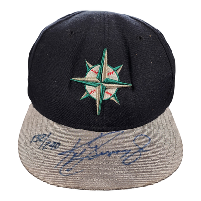 A black and gray mariners baseball cap featuring an embroidered green and white compass star logo on the front, with a blue autograph of ken griffey jr. on the brim.