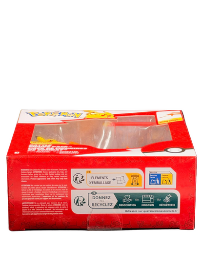 A red Pokémon trading card box with a clear plastic window on top, photographed against a dark black background. The front of the box shows the Pokémon logo and recycling and recycling symbol labels.