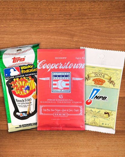 Three vintage baseball trading card packs arranged on a wooden surface: a green and white Topps Wrapper Pack on the left, a red Cooperstown National Baseball Hall of Fame Panini pack in the center, and a white and green NPB 2024 Rookie Pack on the right.