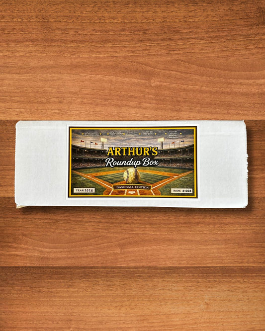 A white rectangular collectible box labeled 'Arthur's Roundup Box' with a baseball stadium graphic, placed on a brown wooden surface.