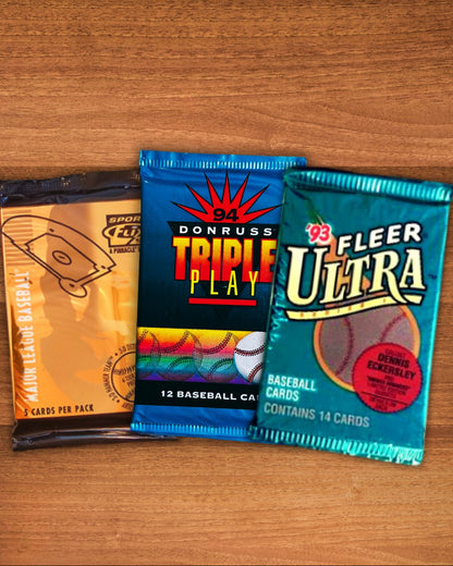 Three vintage baseball trading card booster packs arranged on a wooden tabletop: a tan SPH/Donruss pack on the left, a blue Donruss Triple Play pack in the center, and a teal Fleer Ultra pack on the right.