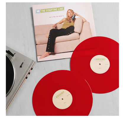 Red vinyl records with a record player and album cover on a gray surface