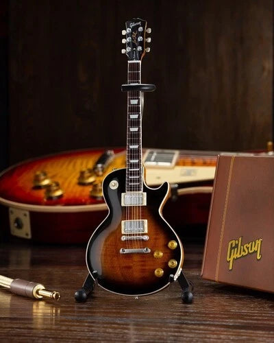 Miniature Gibson electric guitar on a stand with a brown background